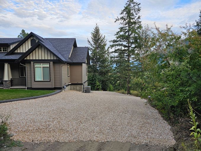 House exterior with gravel yard, scenic mountain view, cloudy sky.