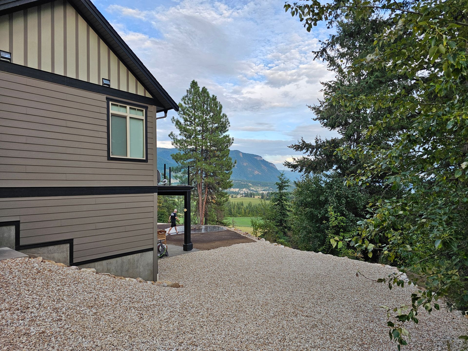 House exterior with gravel yard, overlooking a valley and mountains on a cloudy day.
