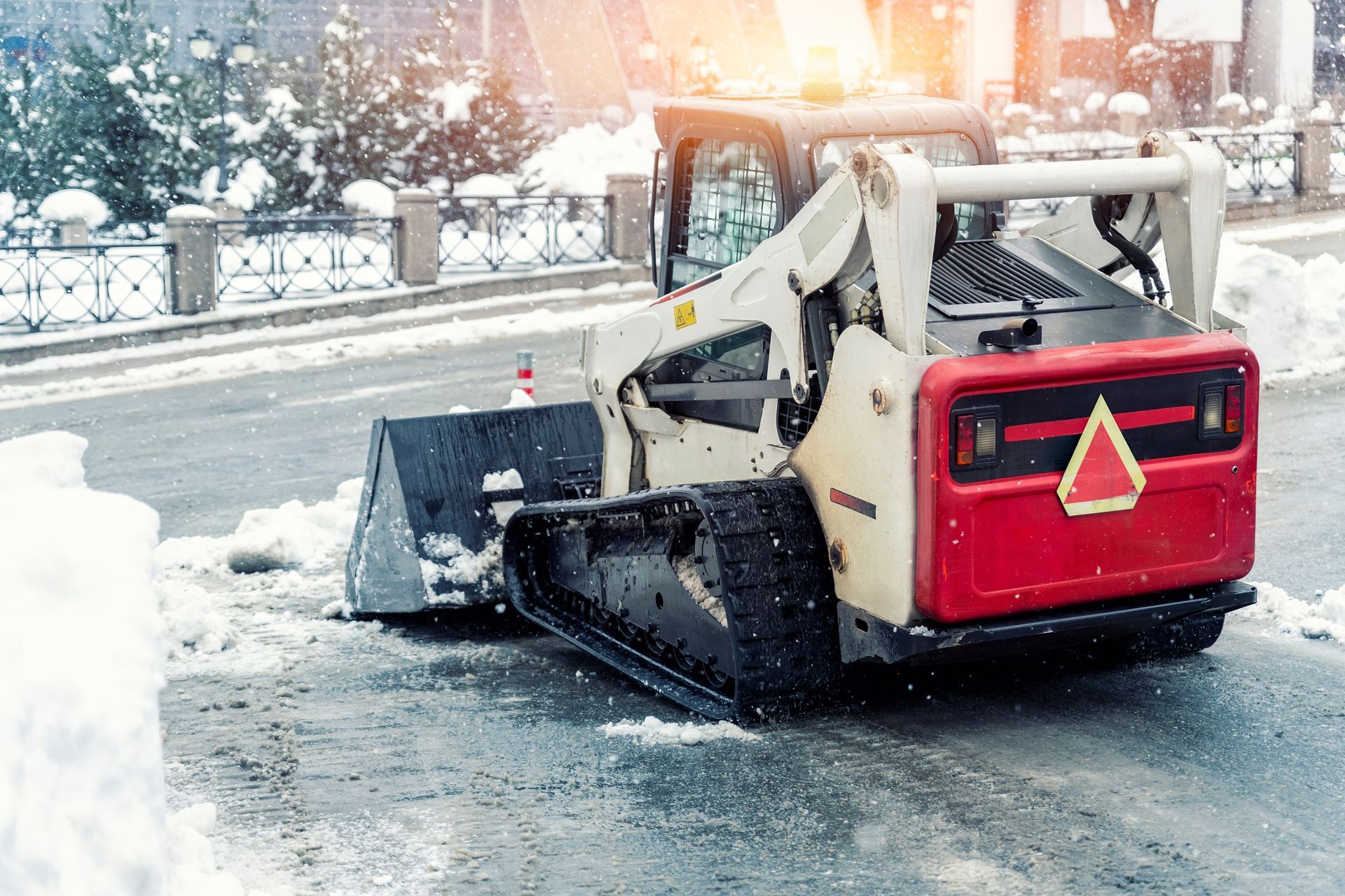 Snowplow clearing snow from a road, white and red machine.