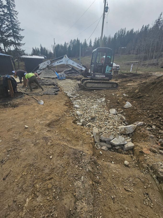 Construction site with a backhoe, debris, and workers clearing rubble.