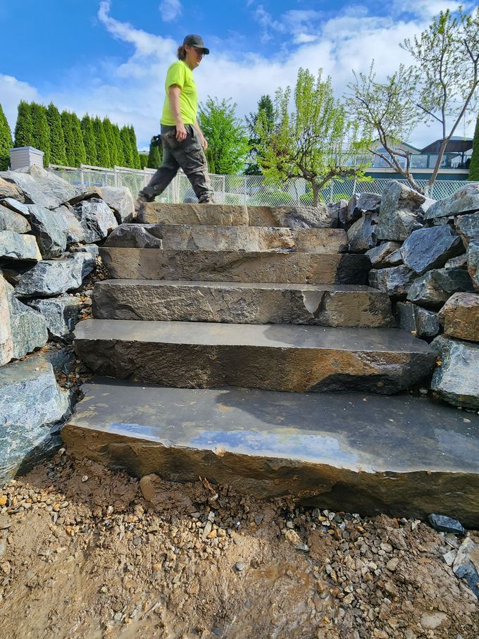 Stone steps with a person walking up, next to rock retaining walls.