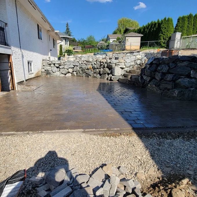 Backyard patio with stone wall and paving stones under construction.