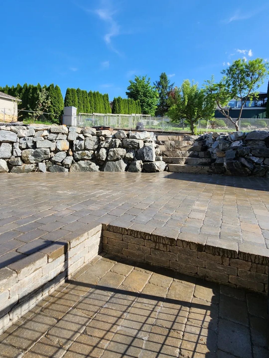 Stone patio with rock walls, steps, and a blue sky.