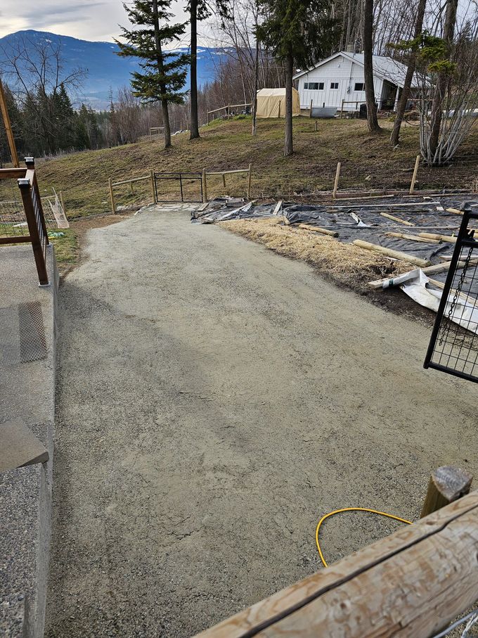 Gravel path leading uphill, with a distant house and mountain backdrop.