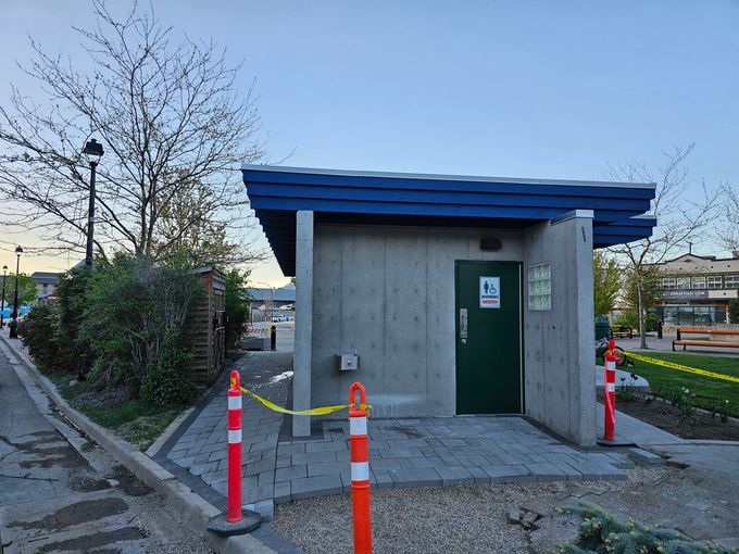 Public restroom with a green door, blue trim, and caution tape.