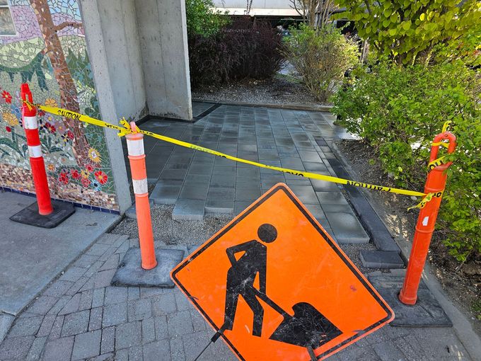 Sidewalk under construction, blocked by caution tape and orange signs.