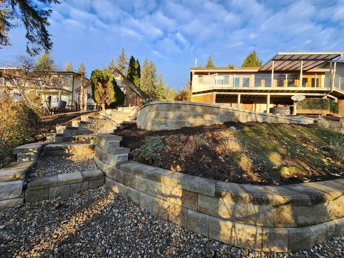 Stone retaining walls and steps lead up to houses, blue sky with clouds.