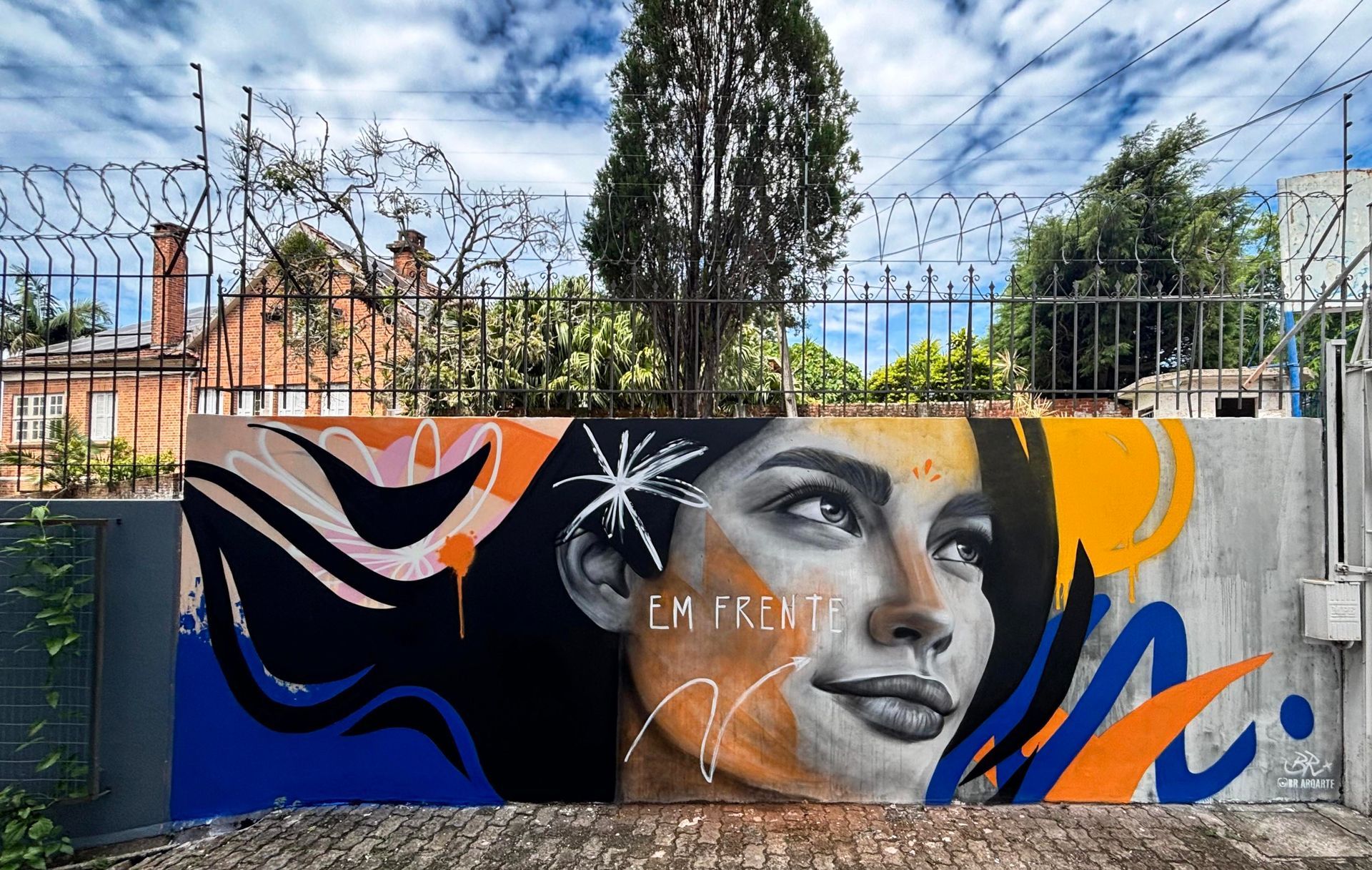 Mural em muro externo de faculdade com figura feminina.