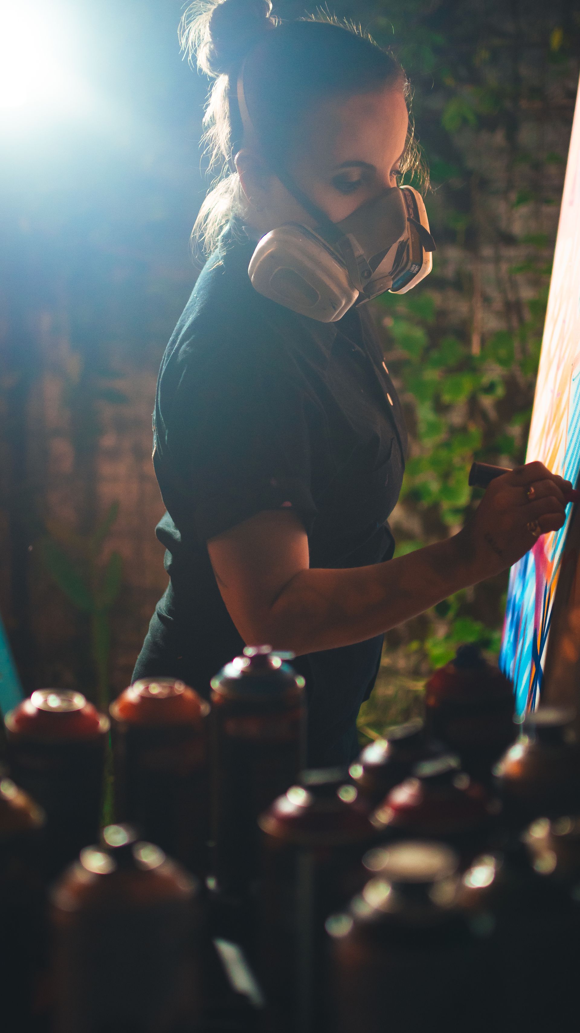 Artista pintando com spray  em uma tela ao ar livre 