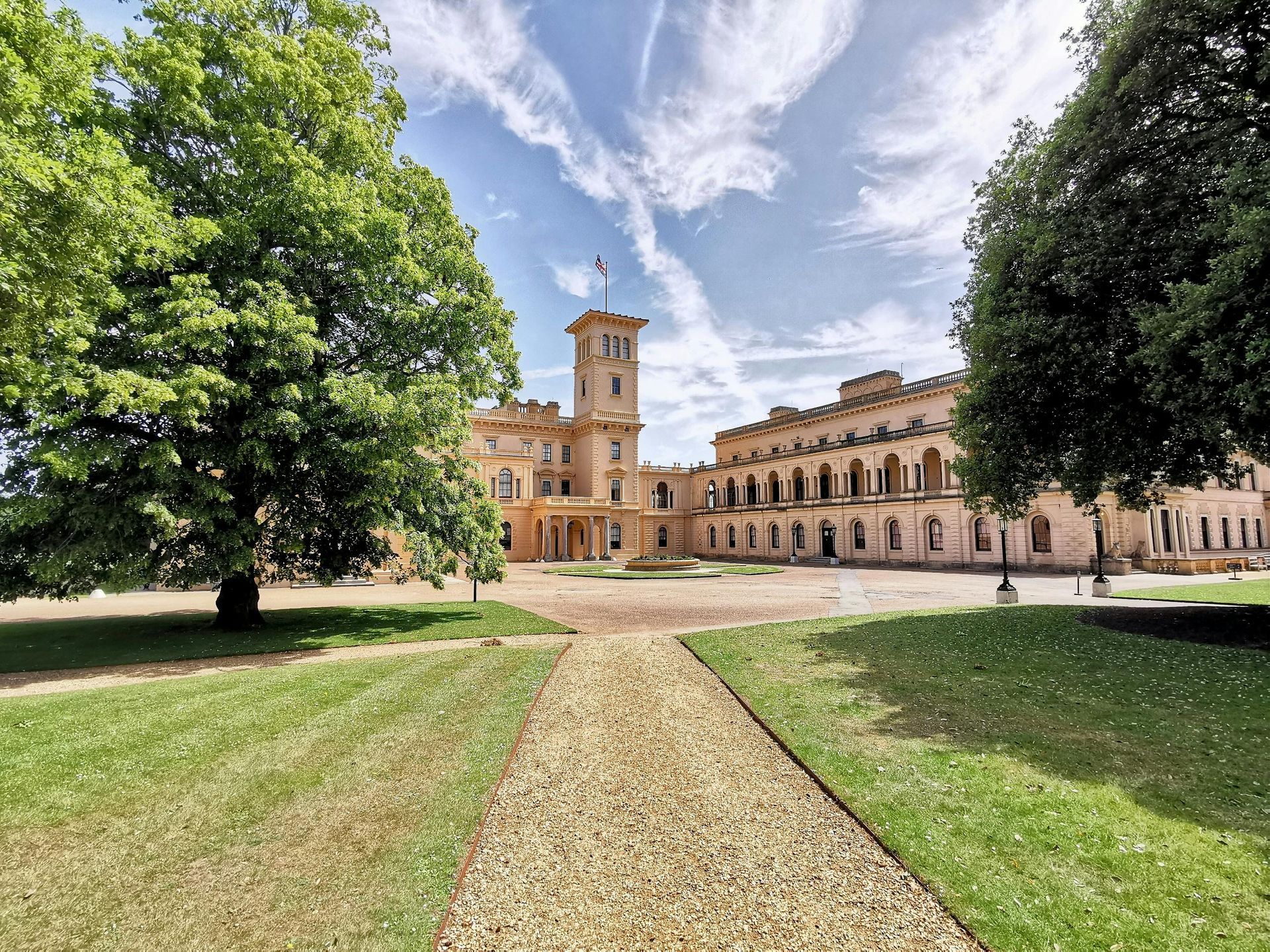 Osborne House, Isle of Wight, with a gravel path leading to the entrance. Sunny day with blue sky and trees.