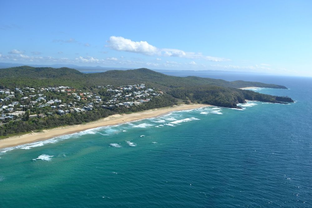 An Aerial View of a Beach Surrounded by Mountains and a Body of Water — We Clean Lounges In Peregian Waters, QLD