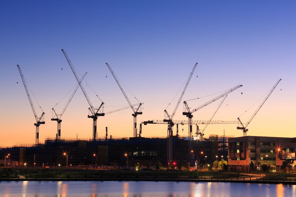 A Row of Cranes and a Sunset Sky Over a Body of Water — We Clean Lounges In Kawana Waters, QLD