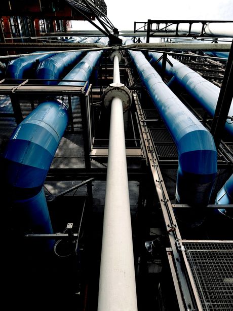Industrial pipes, painted blue and white, run overhead at a facility.