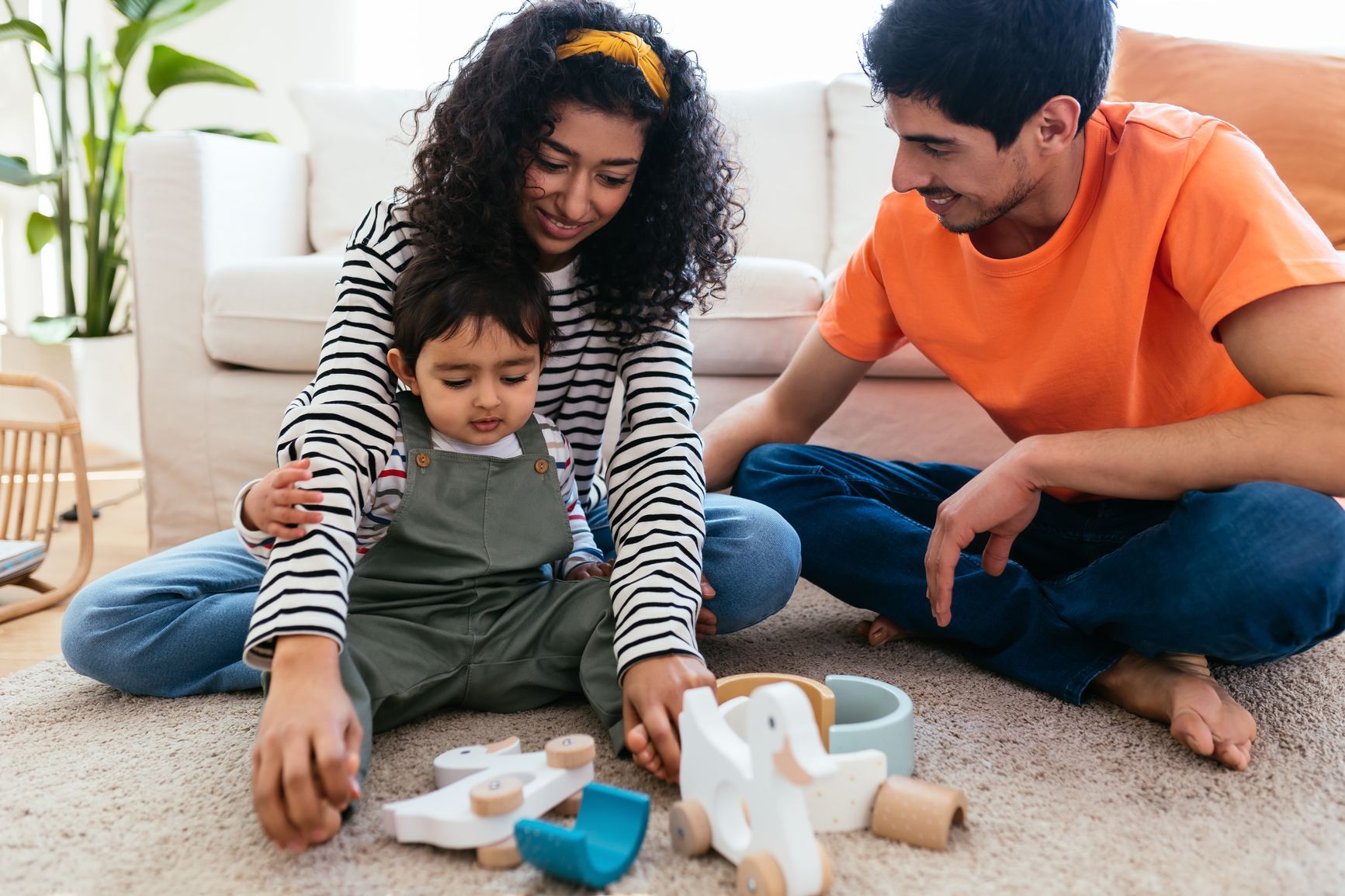 A family is sitting on the floor playing with toys.