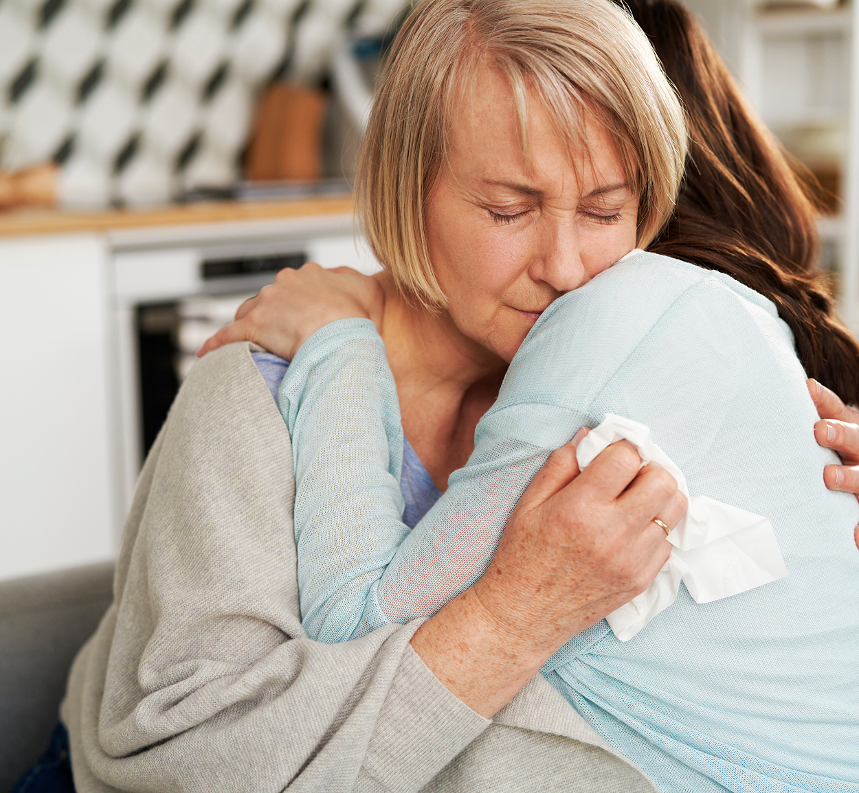 A woman is hugging another woman with her eyes closed.