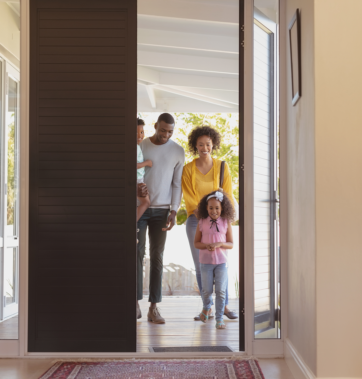 A family is entering a house through a sliding glass door.