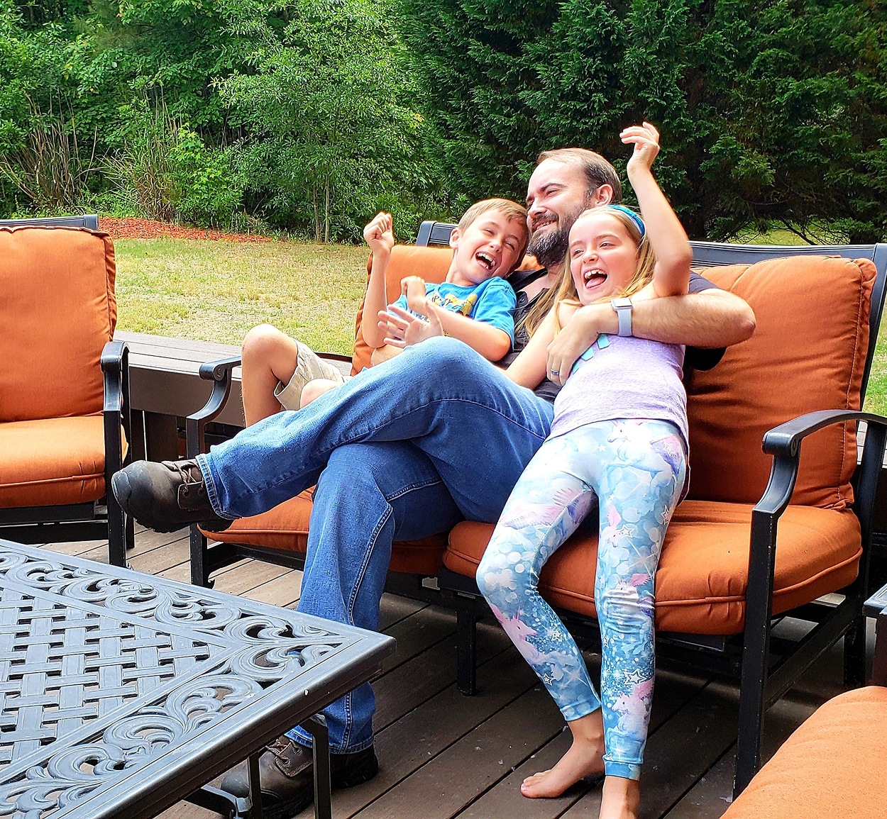 A man sits on a couch with two children on his lap