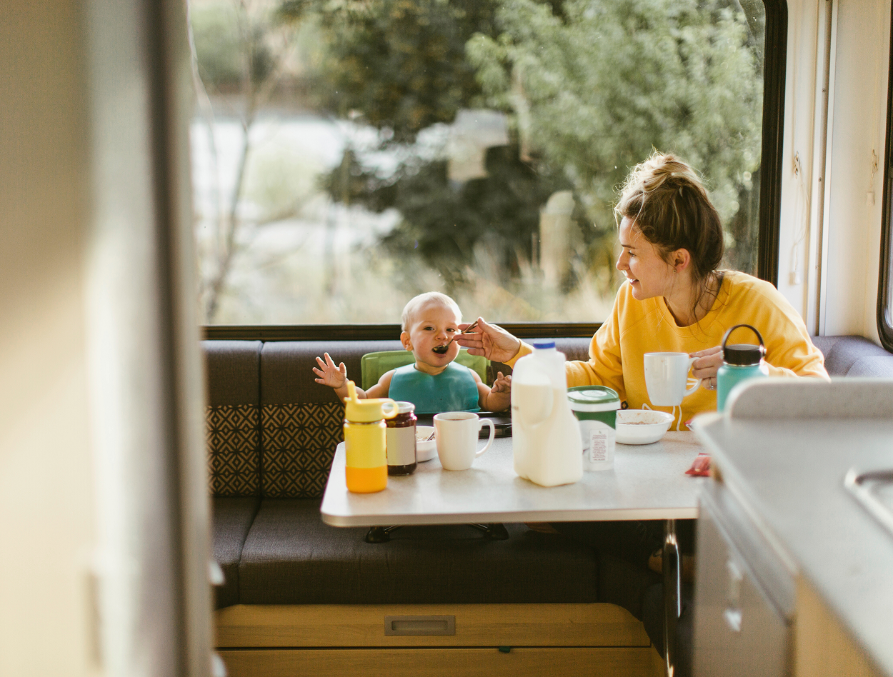 A woman is feeding a baby in a camper.