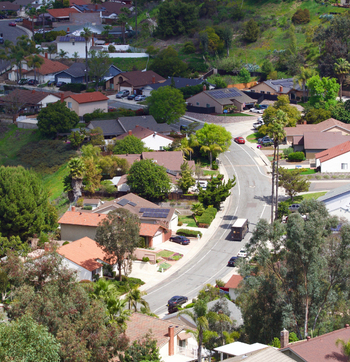 Hillside suburban street lined with houses and trees on a sunny day