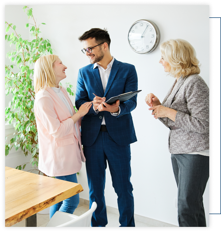 A man in a suit is holding a clipboard and talking to two women