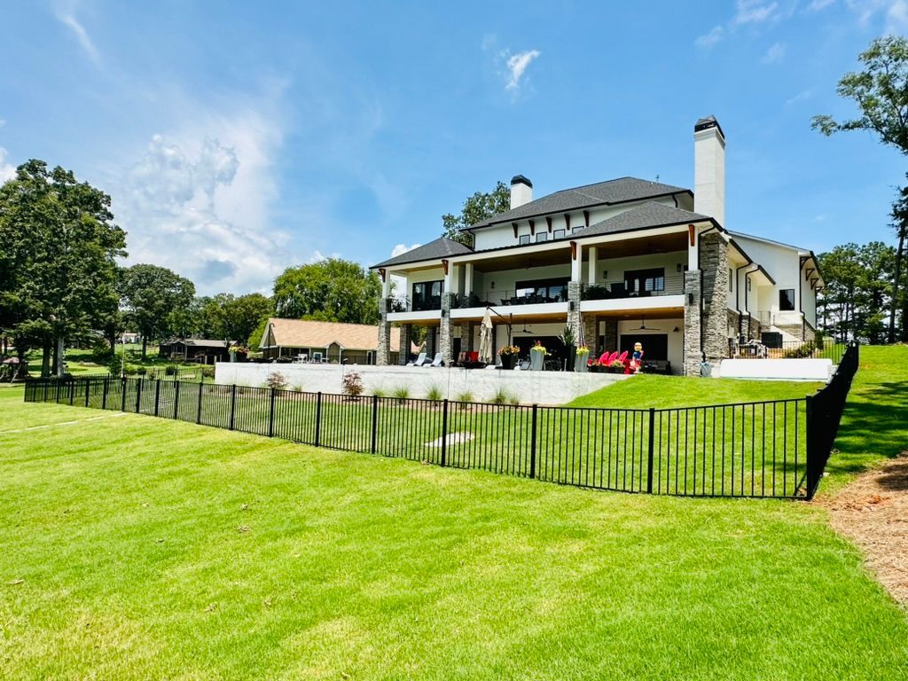 A large house with a fence around it and a large lawn in front of it.