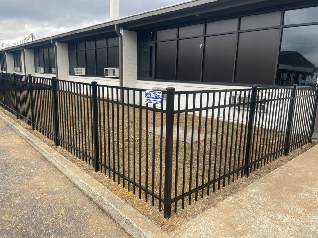 A black fence is surrounding a building with a lot of windows.