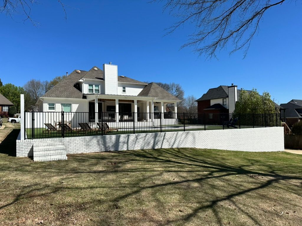 A large white house with a fence around it and a large lawn in front of it.