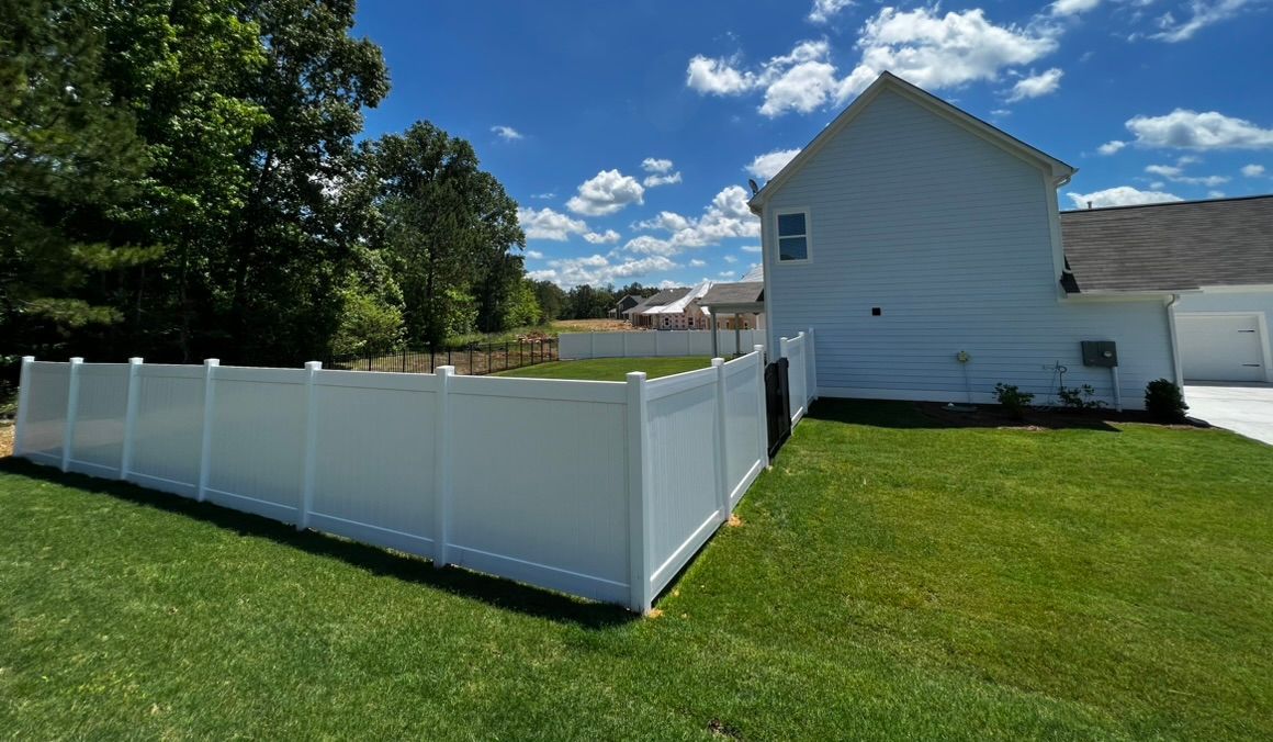 There is a white fence in the backyard of a house.
