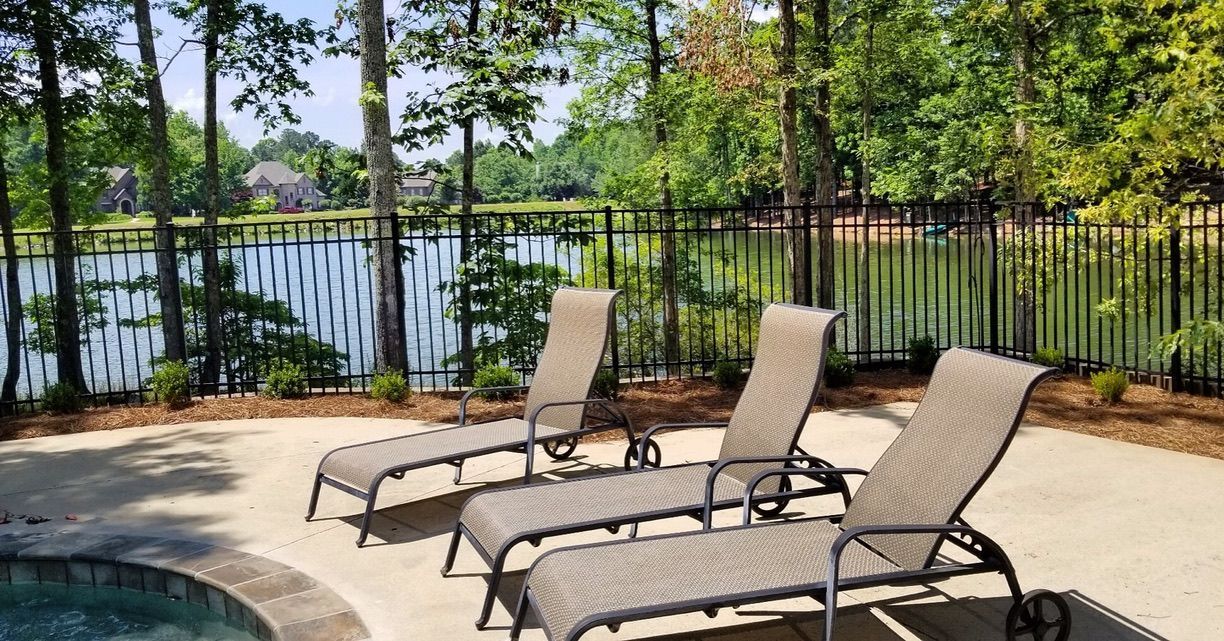 A row of lounge chairs are sitting next to a pool.