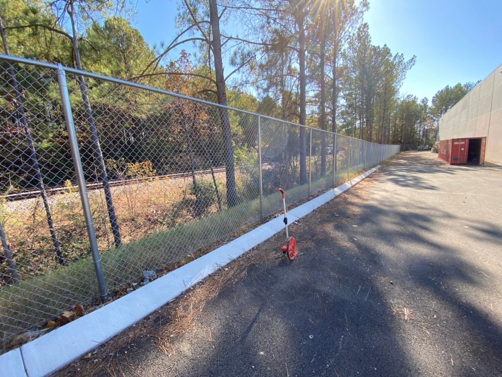 A red scooter is parked next to a chain link fence.