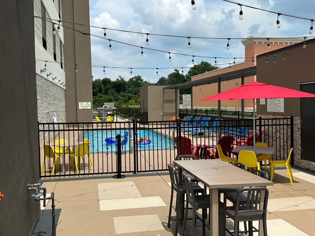 A patio area with tables and chairs next to a pool.