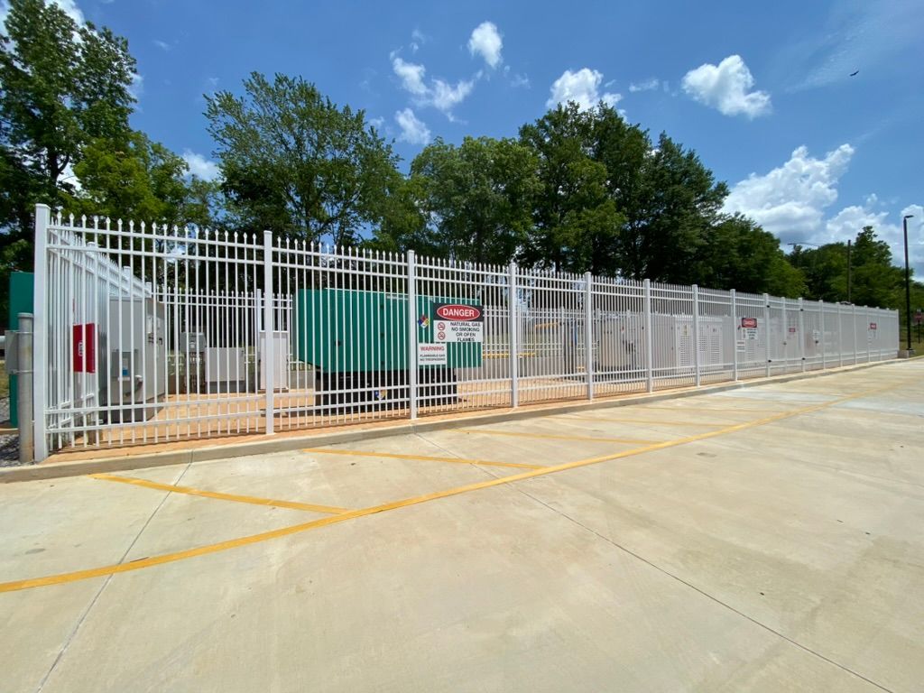 A fence with a danger sign on it is surrounding a parking lot.