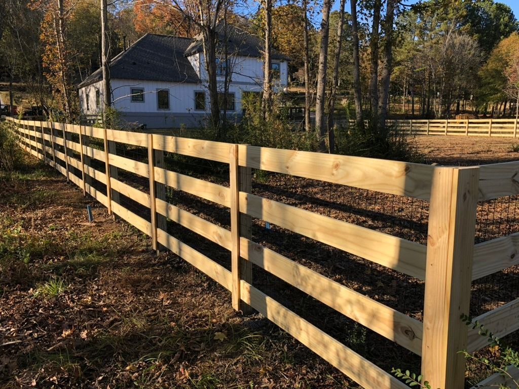 A wooden fence is surrounding a house in the woods.