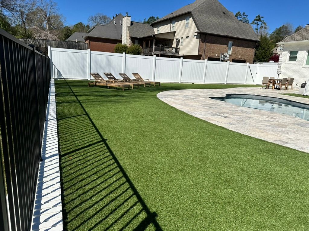 A backyard with a swimming pool and a white fence