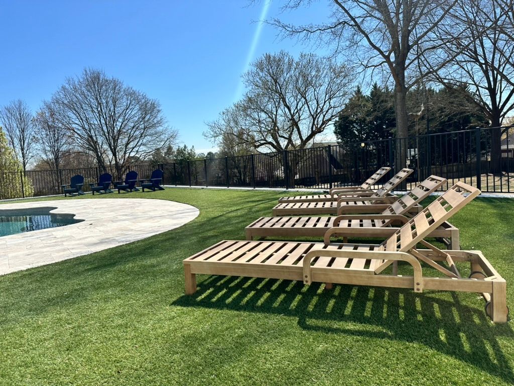 A row of wooden lounge chairs are sitting next to a swimming pool.