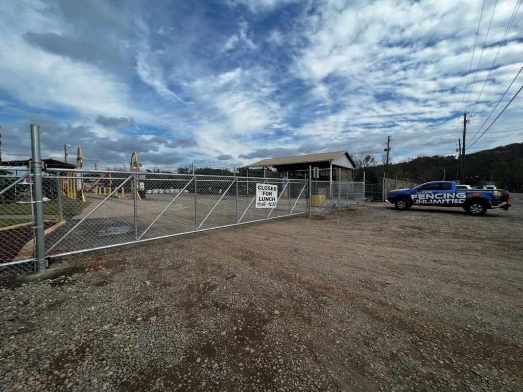 A police car is parked in front of a chain link fence.