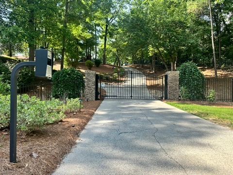 A driveway with a gate and a mailbox on the side of it.
