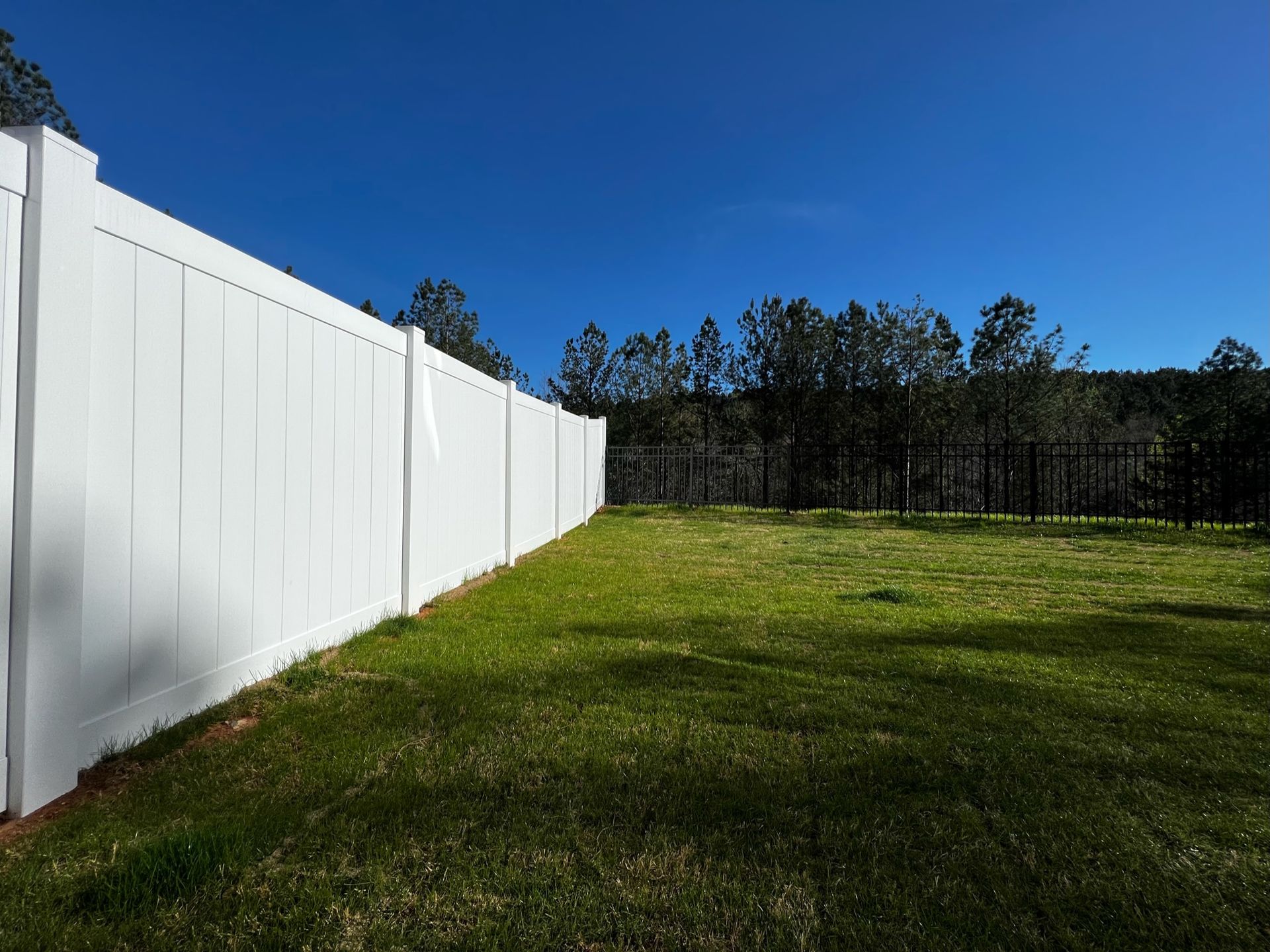 A white fence surrounds a lush green field.