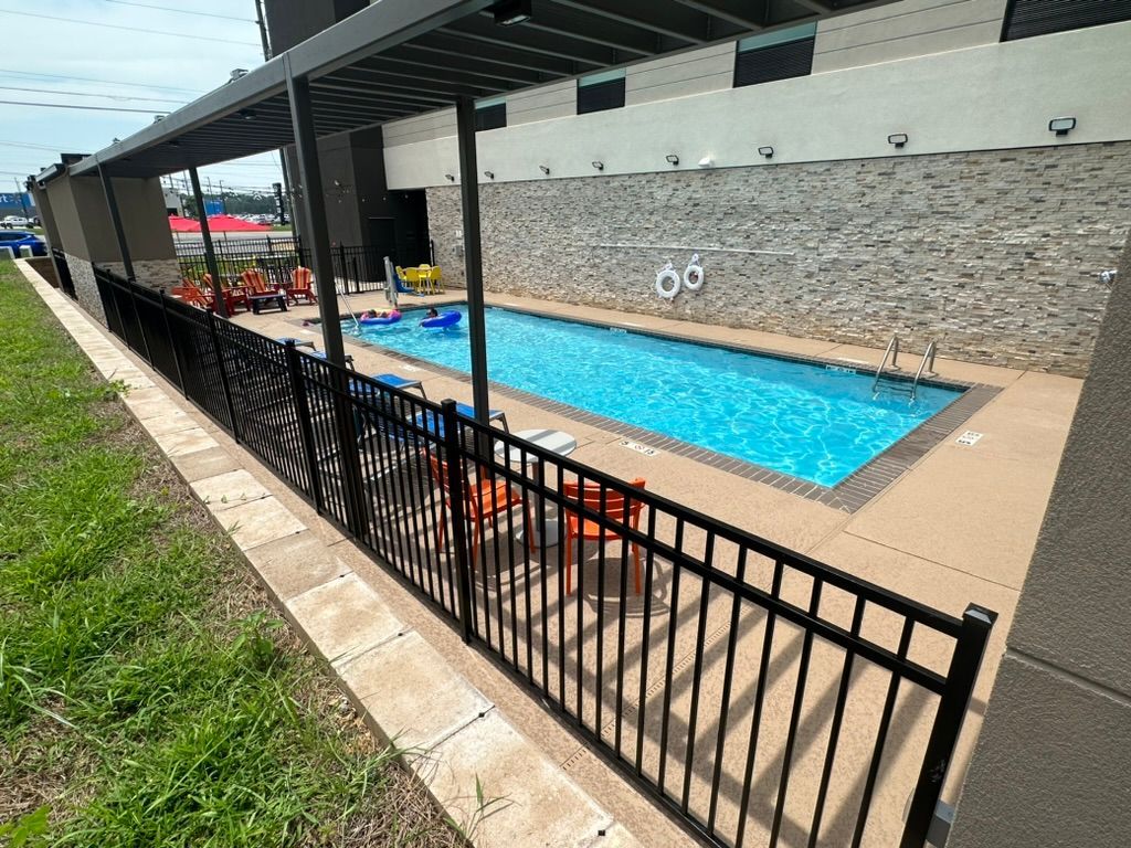 A large swimming pool is surrounded by a metal fence.