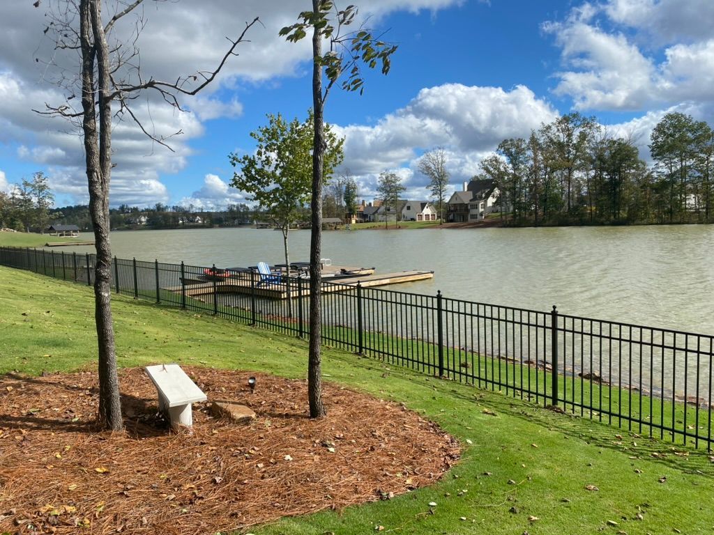 A lake with a fence around it and a bench in the foreground.