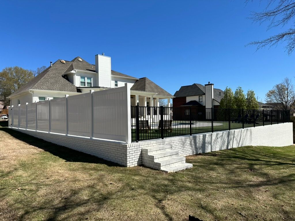 A large white house with a fence around it and a swimming pool.