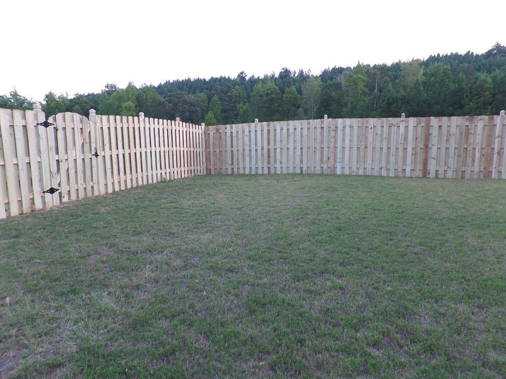 A wooden fence surrounds a lush green field.