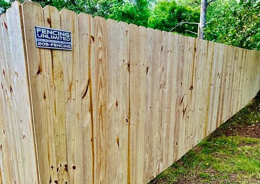 A wooden fence with a sign on it that says `` fencing unlimited ''.