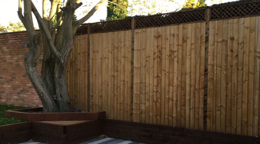 Closeboard wooden fence with lattice trellis toppers in a landscaped garden.