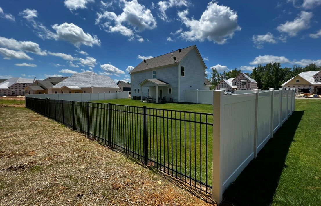 A white fence surrounds a house in a residential area.