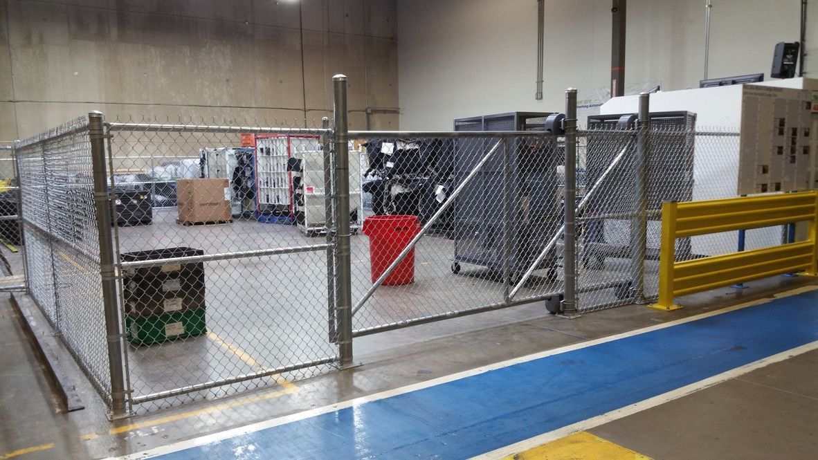 There is a chain link fence in the middle of a warehouse.