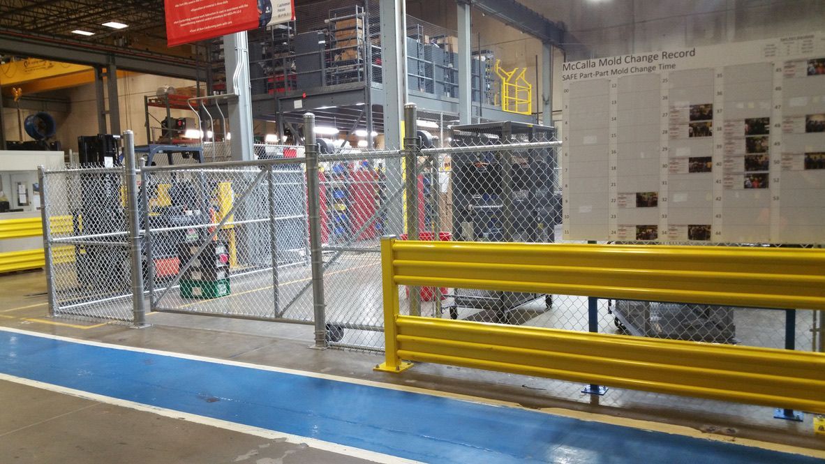 A warehouse with a chain link fence and a blue walkway.