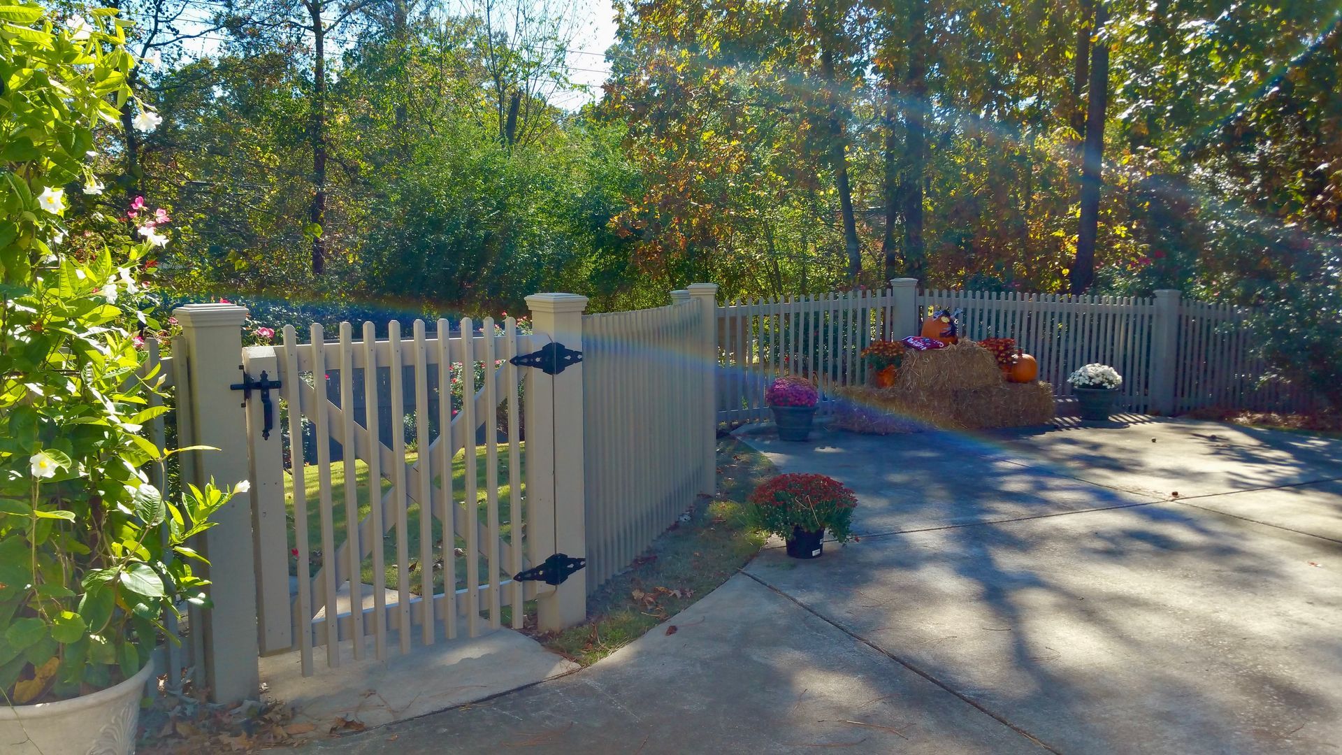 A white picket fence surrounds a driveway leading to a house.
