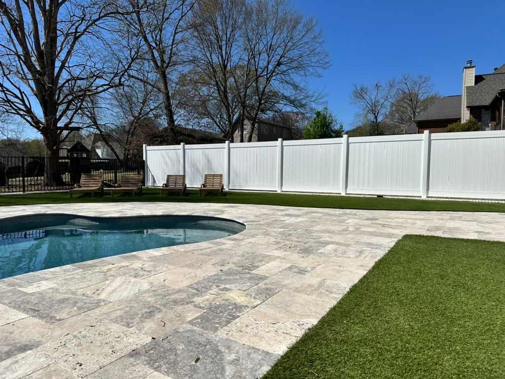 There is a swimming pool in the backyard with a white fence.