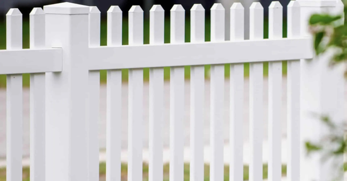 White picket fence, with vertical posts, horizontal rails, and a green background.